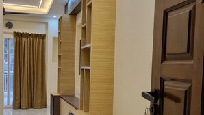 A modern hotel lobby with a marble floor, wooden reception desk, and a closed door. - Airport Inn  (Chennai)
