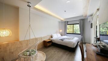 A modern hotel room with a bed, desk, hanging chair, and large window.