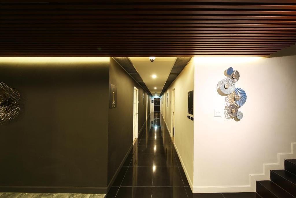 A hallway with a modern design, featuring a dark floor, a ceiling with horizontal lines, and a wall-mounted decorative piece.