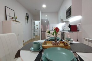 A modern kitchen with a dining area, white cabinetry, and a microwave.