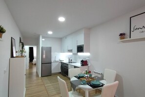 A modern kitchen with white cabinets, stainless steel appliances, and a dining area with a table set for two.