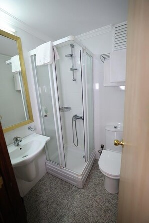 Ein Badezimmer mit Duschkabine, Waschbecken und Toilette.