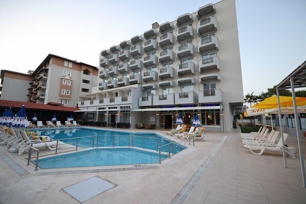 Ein Hotel mit Schwimmbad, mehreren Balkonen und Sitzbereichen im Freien.