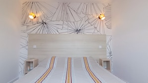 Quarto moderno com uma cama grande, cabeceira com luminária geométrica e mesas de cabeceira.