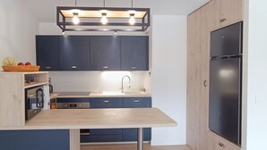 Cozinha moderna com armários azul escuro, bancada de madeira e geladeira de aço inoxidável.