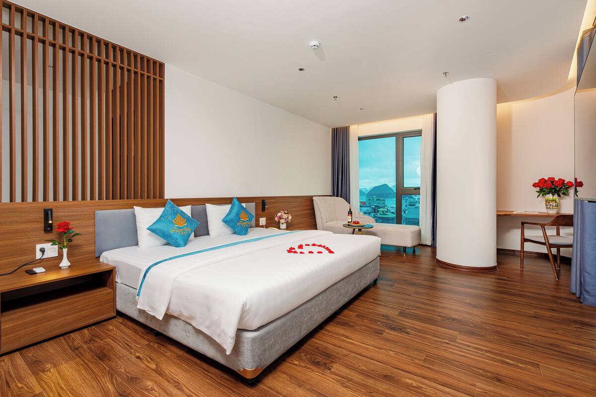 A modern hotel room with a large bed, a desk, and a view of the mountains.