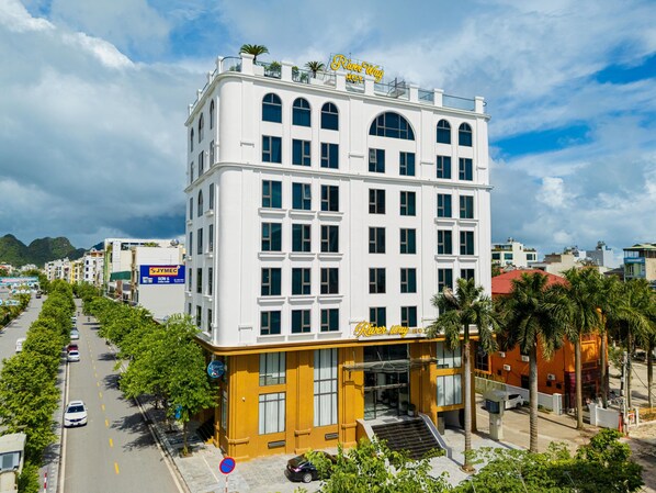 Ett hotell med flera våningar, ett stort skylt med texten ”River Way”, en gul fasad och en trappa som leder upp till entrén.