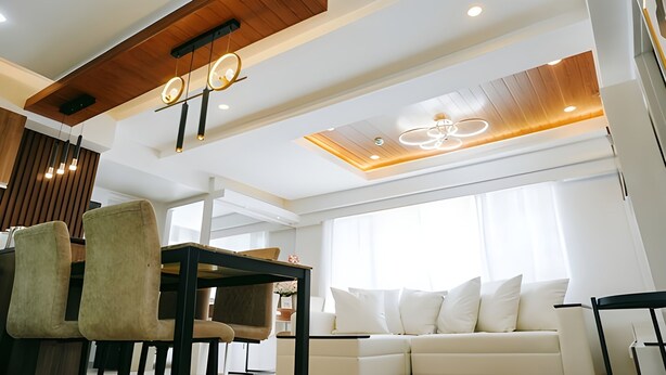Una sala de estar moderna con techo de madera, un sofá y una mesa de comedor con sillas.