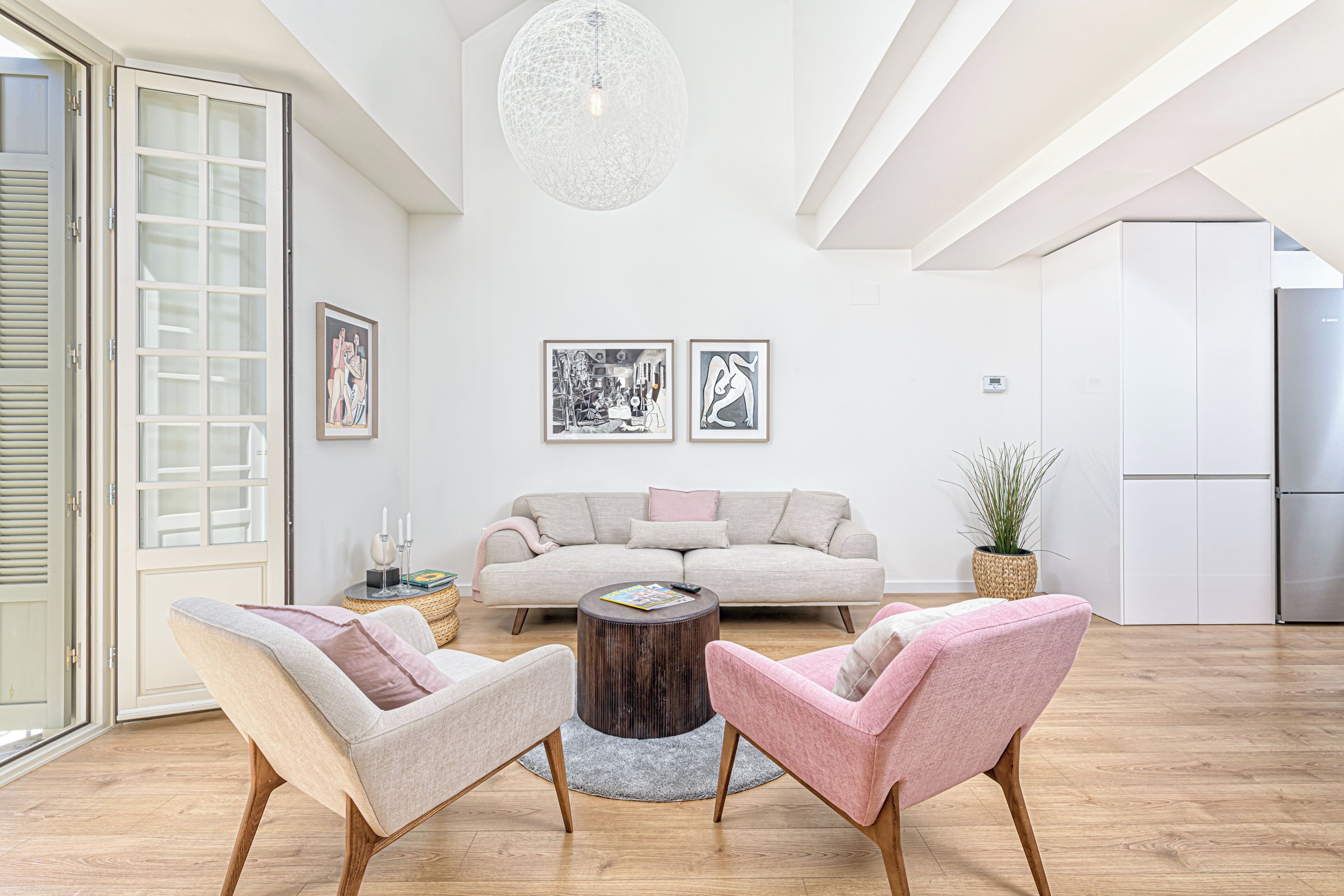 Ein modernes Wohnzimmer mit einer Couch, zwei Sesseln, einem Couchtisch und Kunstwerken an der Wand.