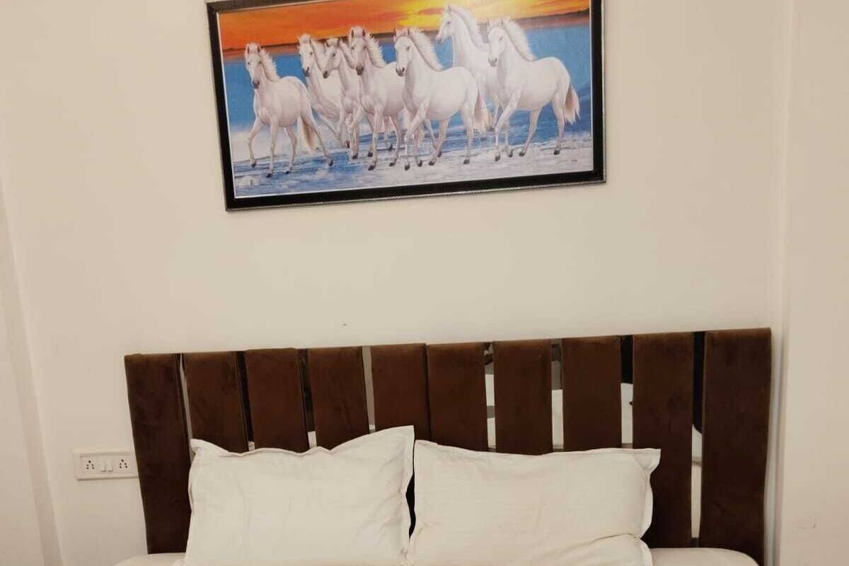 Een hotelkamer met een bed, wit beddengoed, een bruin hoofdeinde en een schilderij van witte paarden aan de muur.
