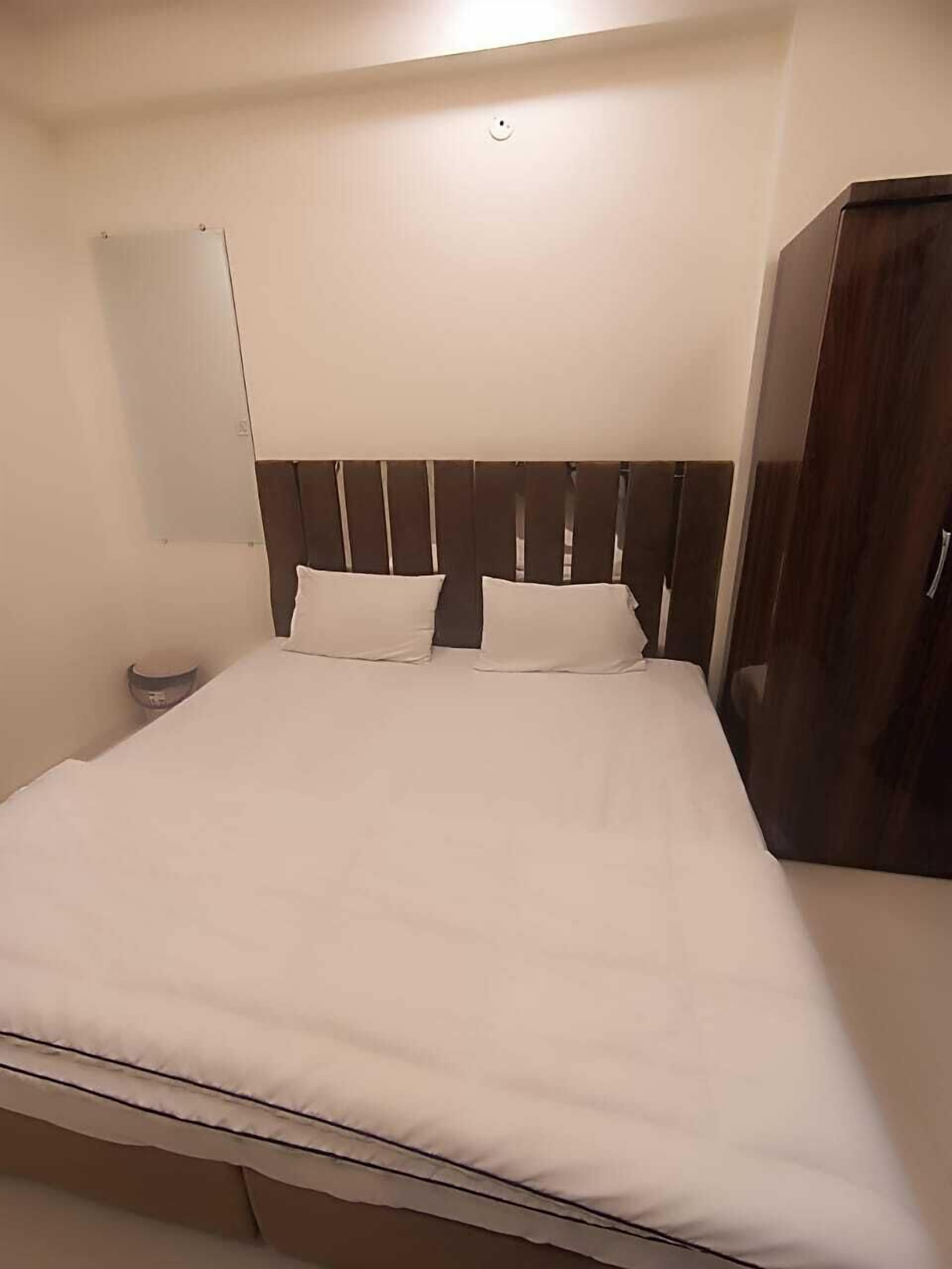 A single bed with a wooden headboard, a bedside table, and a wardrobe.