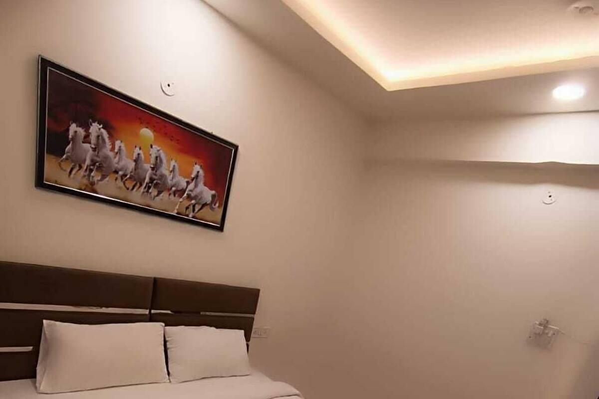 Een netjes opgemaakt bed met decoratieve kussens, een hoofdbord en een schilderij van paarden aan de muur.