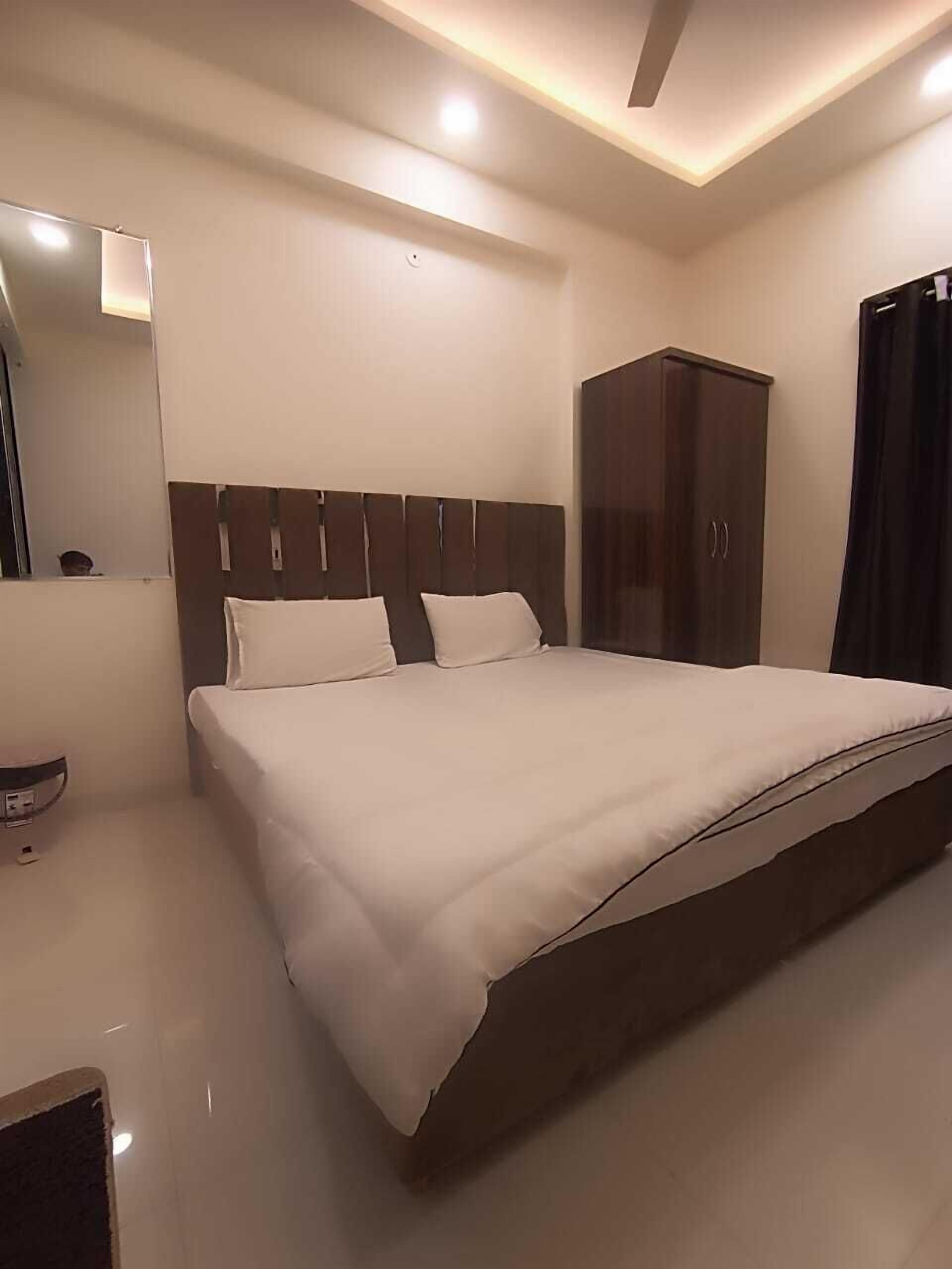 A modern bedroom with a large bed, a wardrobe, and a mirror.