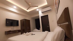 Ein modernes Hotelzimmer mit einem großen Bett, einem Flachbildfernseher, einem Kleiderschrank und einer Klimaanlage.