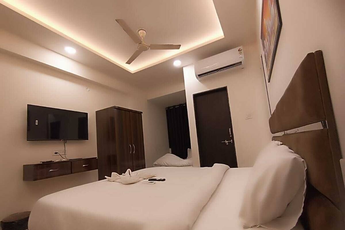 Een moderne hotelkamer met een groot bed, een flatscreen televisie, een kledingkast en een airconditioning.