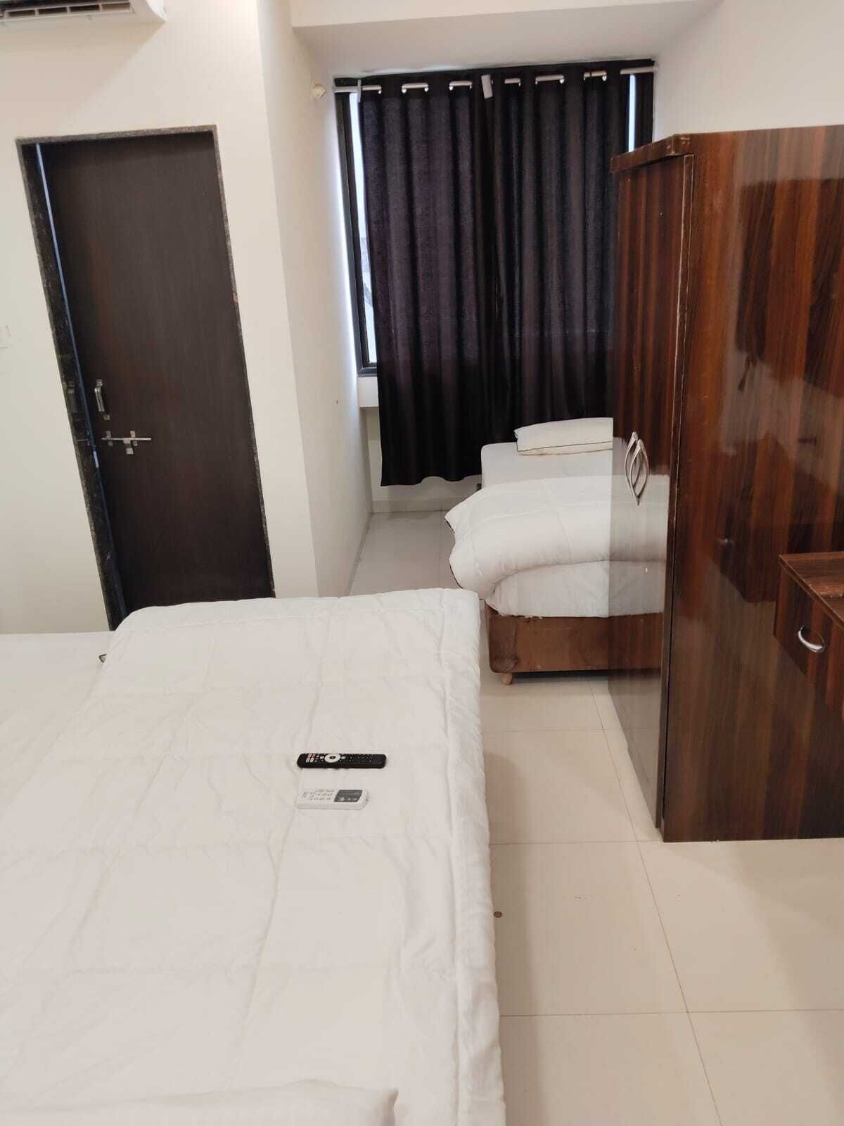 A bedroom with a bed, a wardrobe, and a window with curtains.