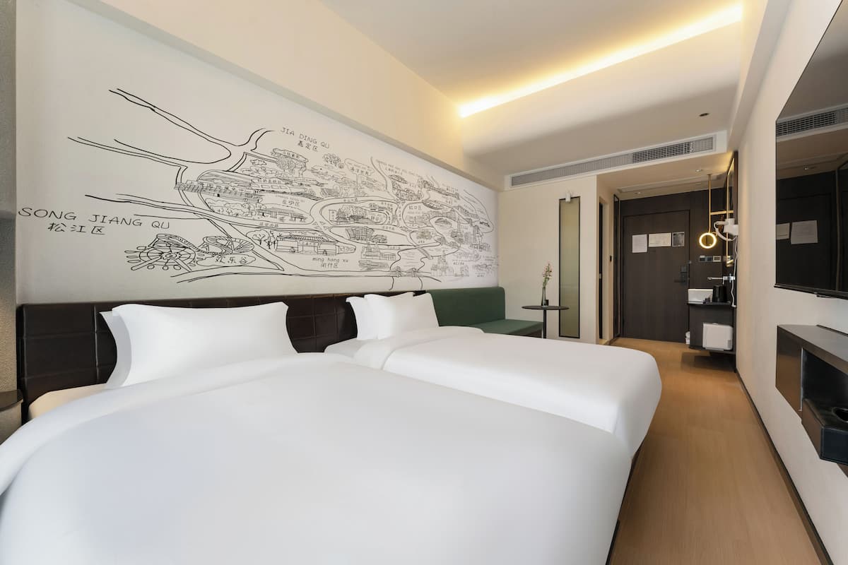 Ein Hotelzimmer mit einem großen Bett, einem grünen Sofa, einer Wandkarte und einem kleinen Tisch mit Lampe.