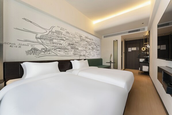 Ein Hotelzimmer mit einem großen Bett, einem grünen Sofa, einer Wandkarte und einem kleinen Tisch mit Lampe.