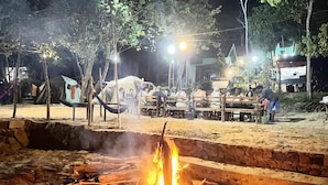 A campfire with tents and people in the background. - Plankton Bungalow and Camping (Koh Rong)