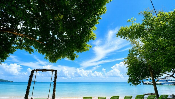 A beach with a swing set, green lounge chairs, and a clear view of the ocean. - Plankton Bungalow and Camping (Koh Rong)