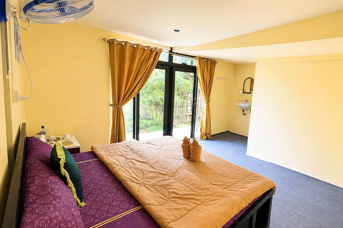 A room with a bed, a window, a sink, and a fan.