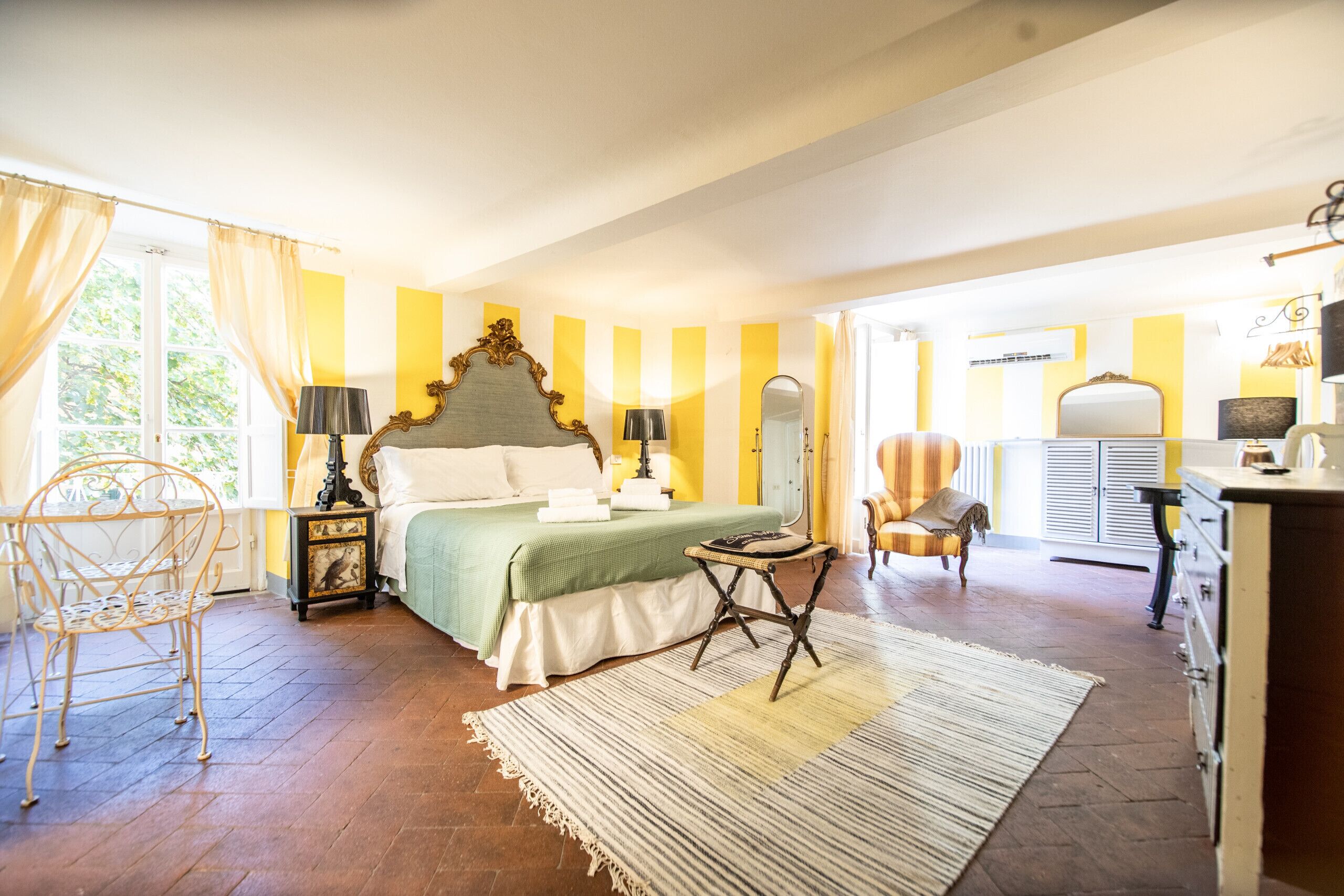 Una camera da letto con un letto, un comodino, una lampada, una sedia e un comò.