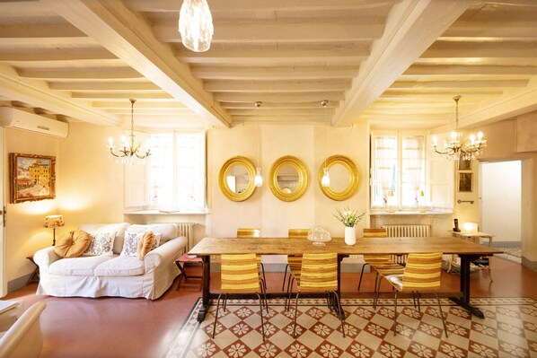 Un comedor con mesa de madera, sillas a rayas y alfombra estampada.