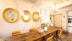 Un coin repas avec une table en bois, quatre chaises et trois miroirs encadrés de doré accrochés au mur.