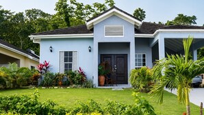 A light blue house with a dark front door, a small porch, and a well-maintained garden.