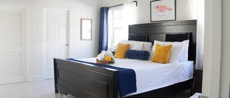 A bedroom with a bed, a bedside table, a wall-mounted air conditioner, and a framed map.