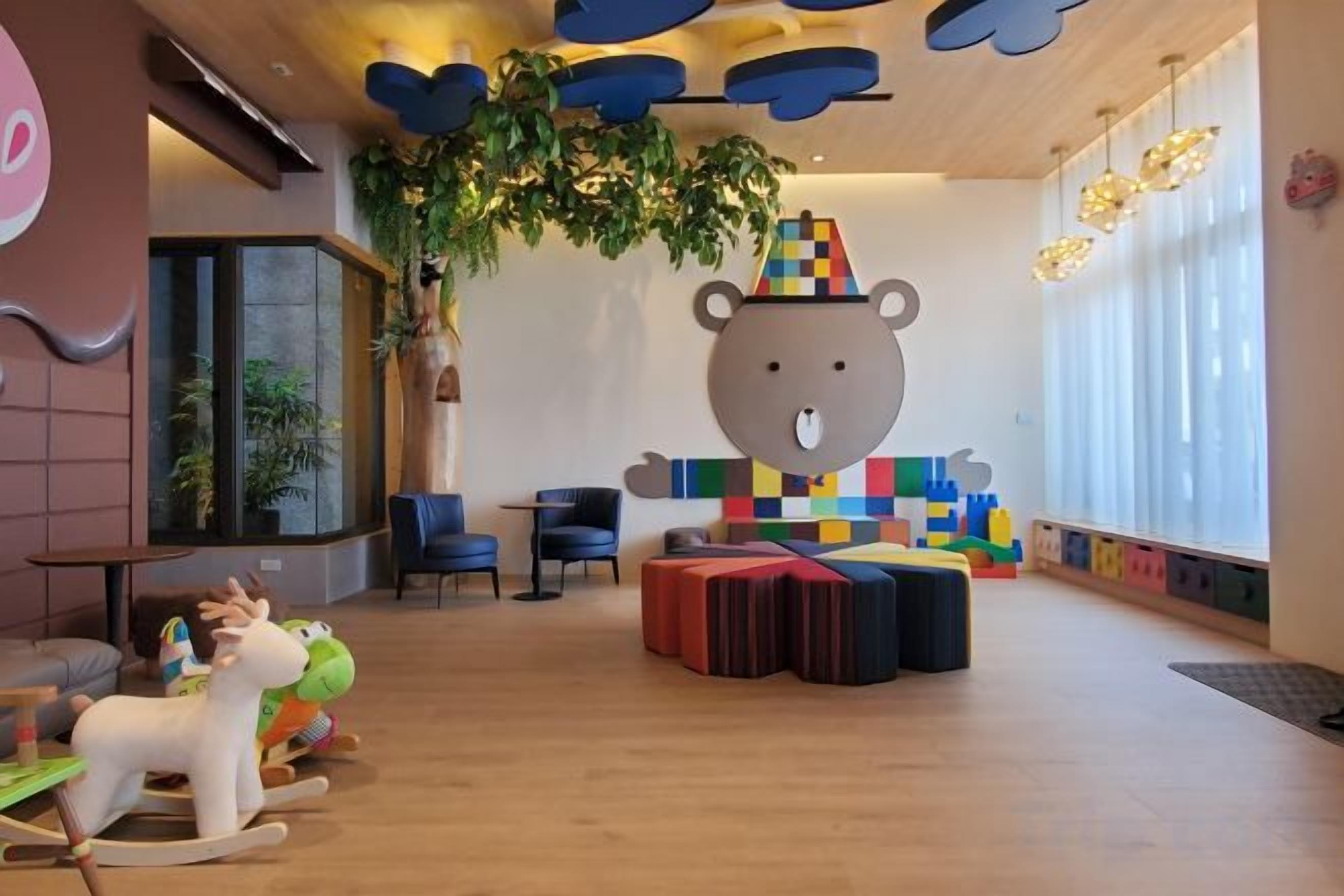 A children's play area with a large bear decoration, seating, and toys.