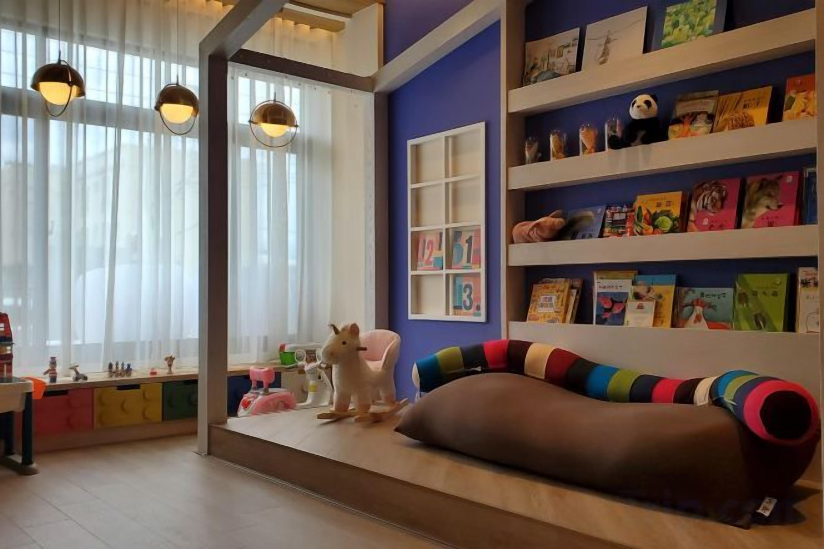 A children's play area with a sofa, shelves with books, and a cat statue.