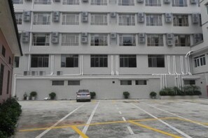 A multi-story building with a parking lot in front. - Jiangmen Mintai Hotel (Jiangmen)