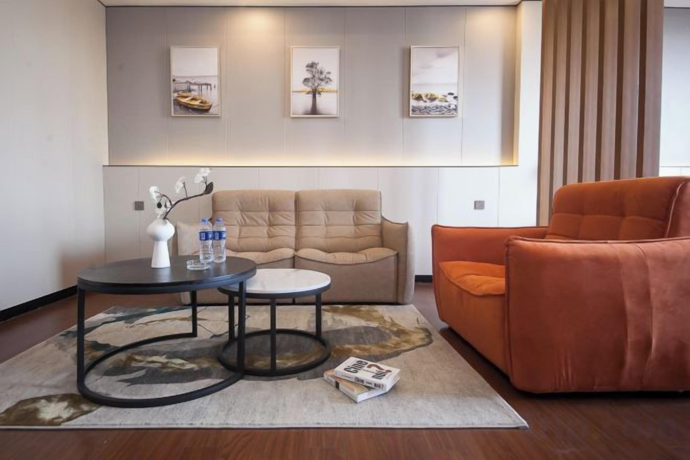 A modern living room with a sofa, two side tables, and a coffee table. There are framed pictures on the wall and a magazine on the floor.