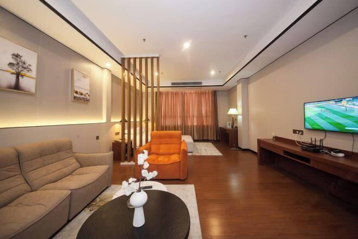 A modern living room with a sofa, a chair, a TV, and a decorative vase.