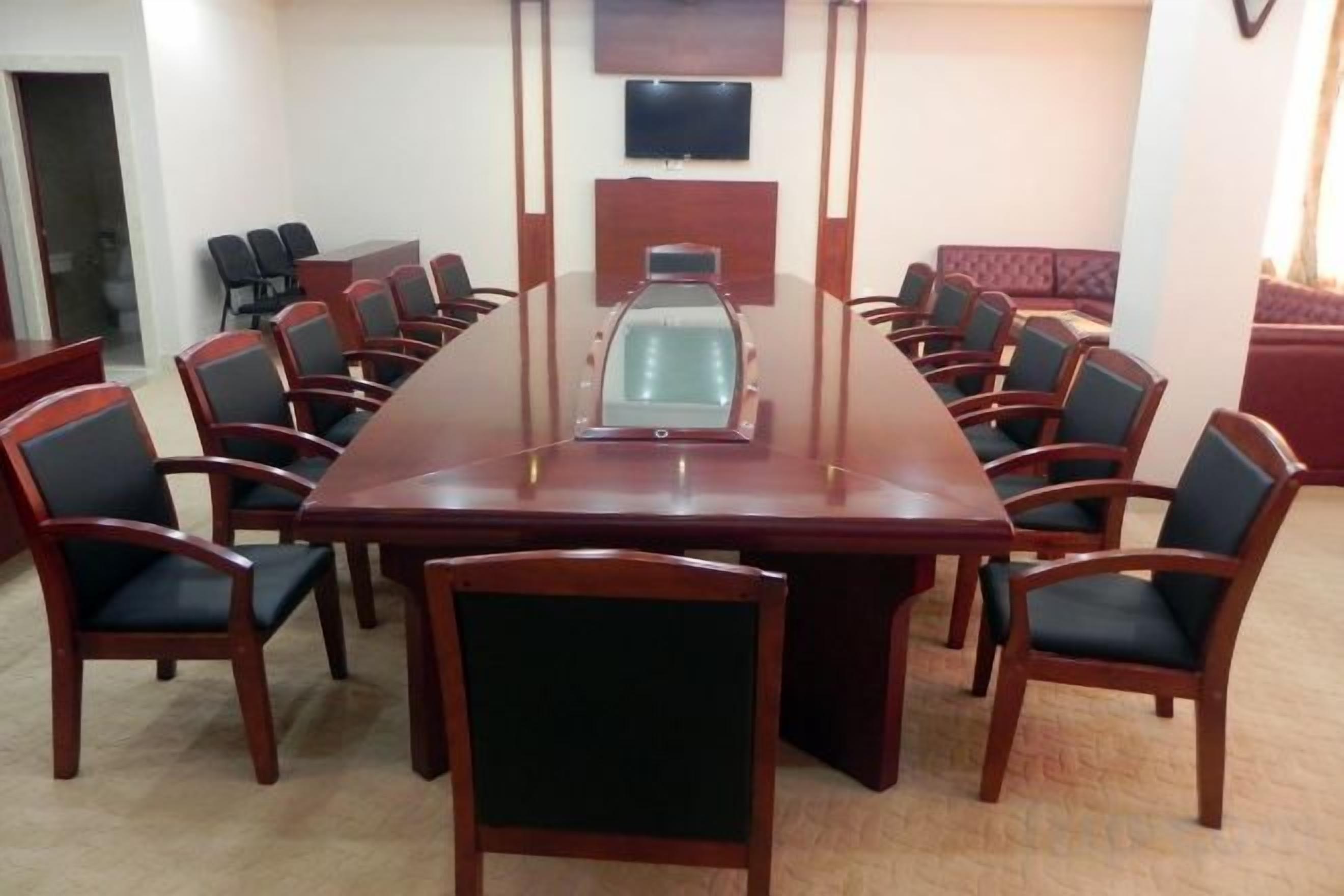 A conference room with a long table and chairs, a television screen, and a carpeted floor.