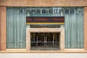 A hotel entrance with a large sign above the door, a glass entrance, and a tiled ground. - Jiangmen Mintai Hotel (Jiangmen)