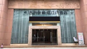 A hotel entrance with a large glass door, a sign above the door, and a small signboard to the right. - Jiangmen Mintai Hotel (Jiangmen)