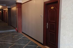 A hotel corridor with a wooden door, a number plaque, and a carpeted floor. - Jiangmen Mintai Hotel (Jiangmen)