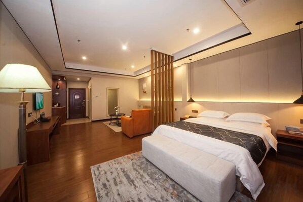 Una habitación de hotel moderna con una cama grande, mesitas de noche, un escritorio y una zona de estar.