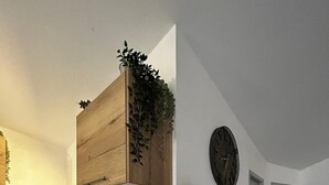 Et moderne køkken med et hvidt køleskab, et rødt og hvidt backsplash, et træskab, en kaffemaskine, en brødrister og et ur på væggen.