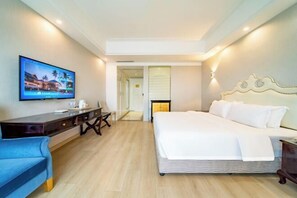 A hotel room with a bed, a desk, a TV, and a chair.