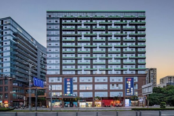 A multi-story hotel with a modern design, featuring a prominent entrance with signage and a series of balconies on each floor.