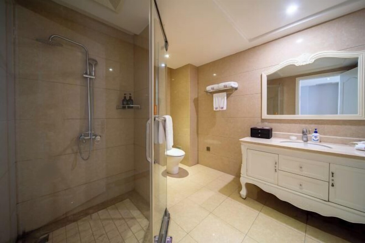 A bathroom with a glass-enclosed shower, a toilet, a vanity with a mirror, and a towel rack.