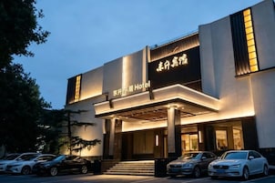 Un hotel con fachada moderna, señalización iluminada y una zona de acceso cubierta.