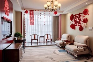 A living room with a sofa, chairs, a TV, and a chandelier. - Dongsheng Hotel (Zouping)