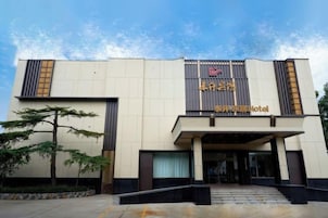 A hotel entrance with a modern design, featuring a prominent sign and a covered entrance area.