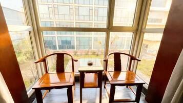 A room with a large window, two wooden chairs, and a small table.