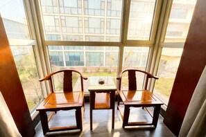 A room with a large window, two wooden chairs, and a small table. - Dongsheng Hotel (Zouping)