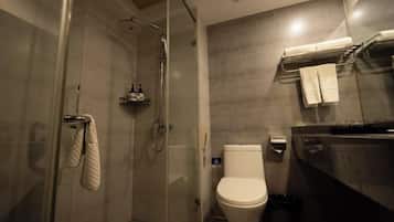 A bathroom with a glass-enclosed shower, a toilet, and a towel rack with towels.